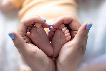 Frontend mom holds legs newborn baby her hands  2 